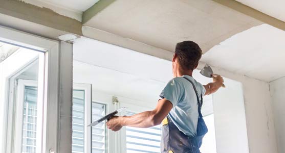 Handwerker zieht Innenputz an einer Decke ab